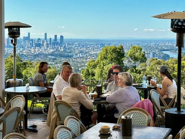 People enjoy drinks on an outdoor terrace with city views.