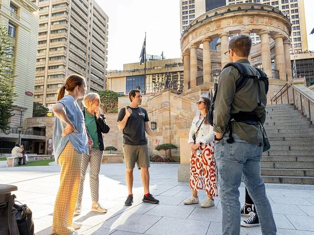Tour group stands outdoors in a city square.