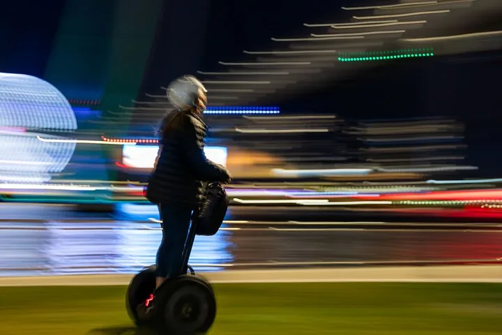Verschwommene Bewegungsaufnahme einer Person, die auf einem Segway fährt.